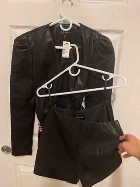 The Sand Black Faux Leather Puff-Sleeve Blazer with Gold Chain Belt with shorts